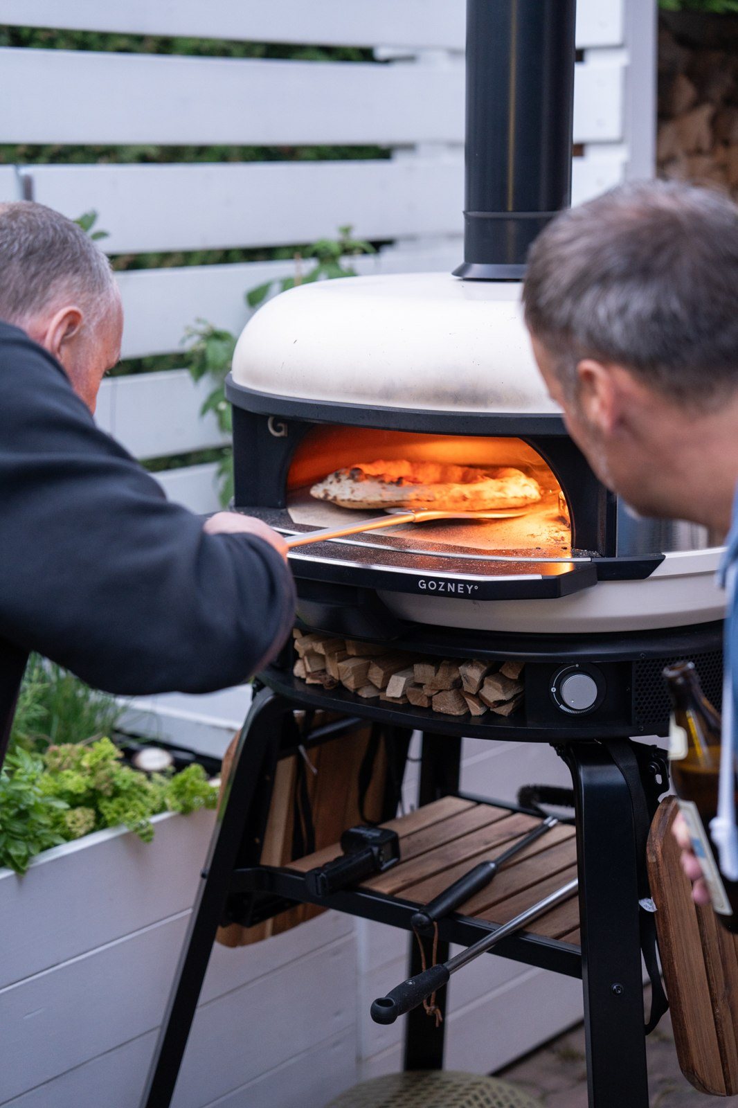 Zwei Männer schauen gemeinsam nach einer Pizza im heißen Ofen.