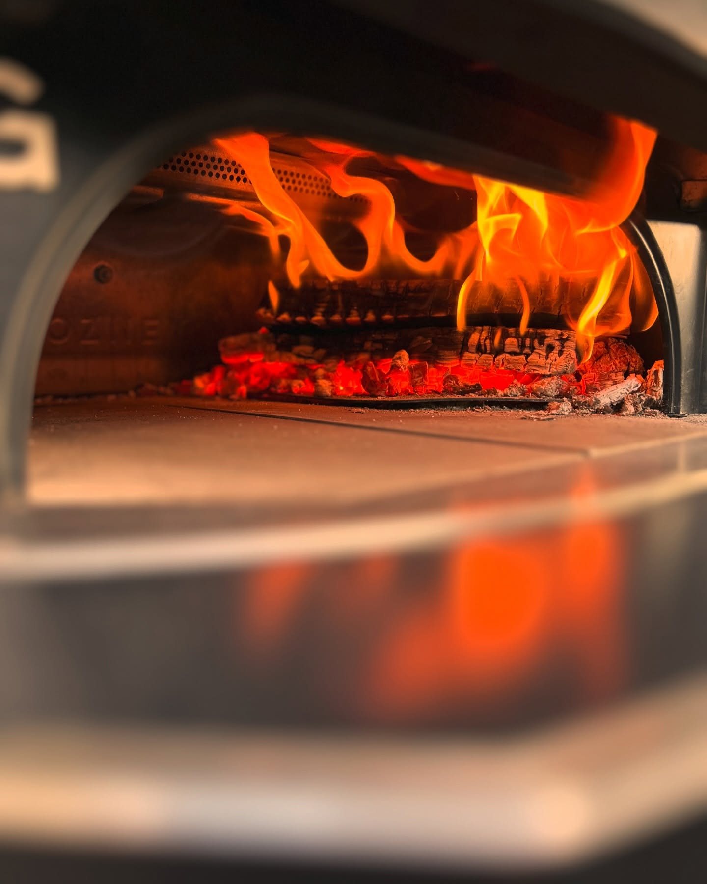 Flammen und glühendes Holz im aufgeheizten Pizzaofen.